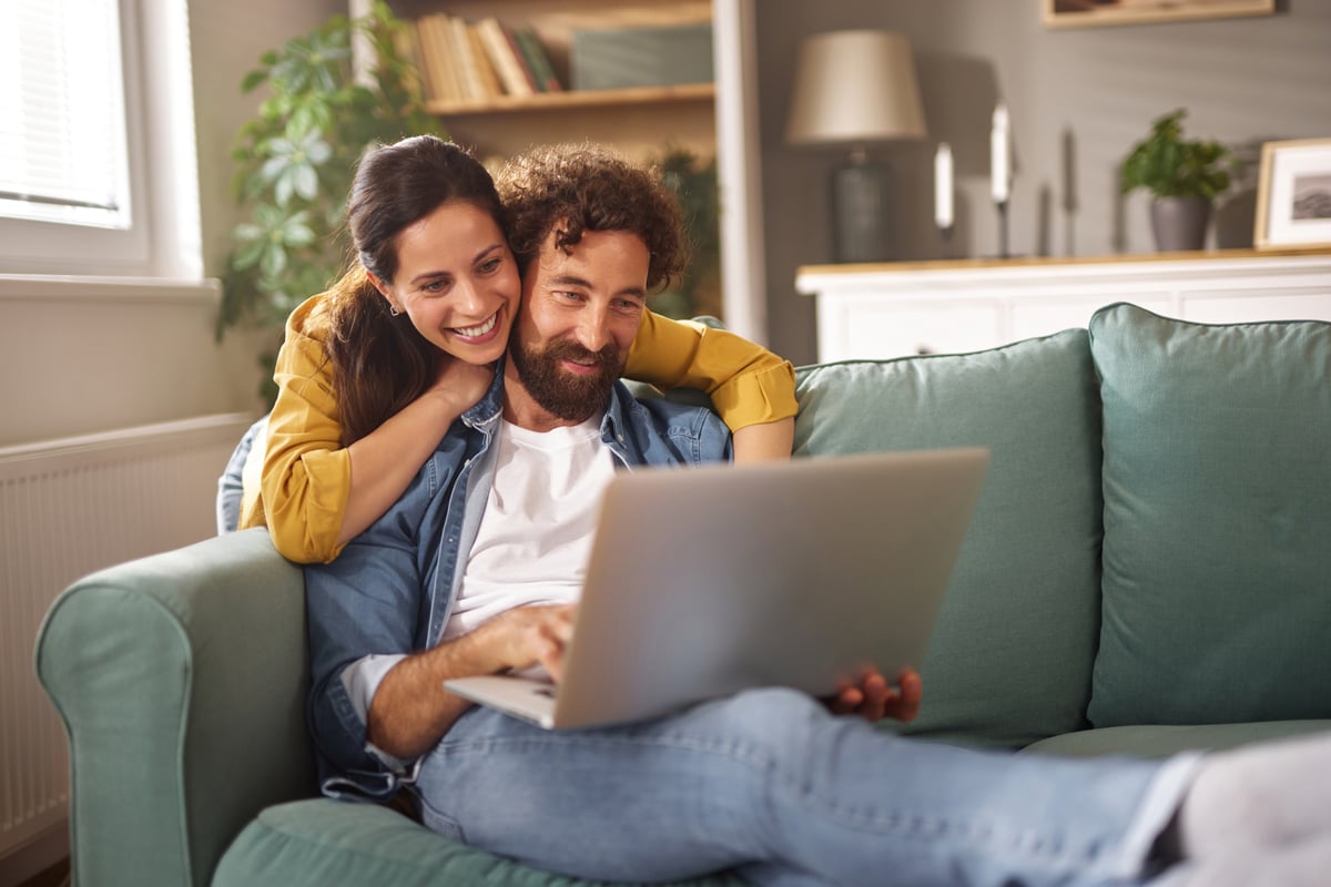 Pareja cotizando su inversión desde el sofá con una laptop