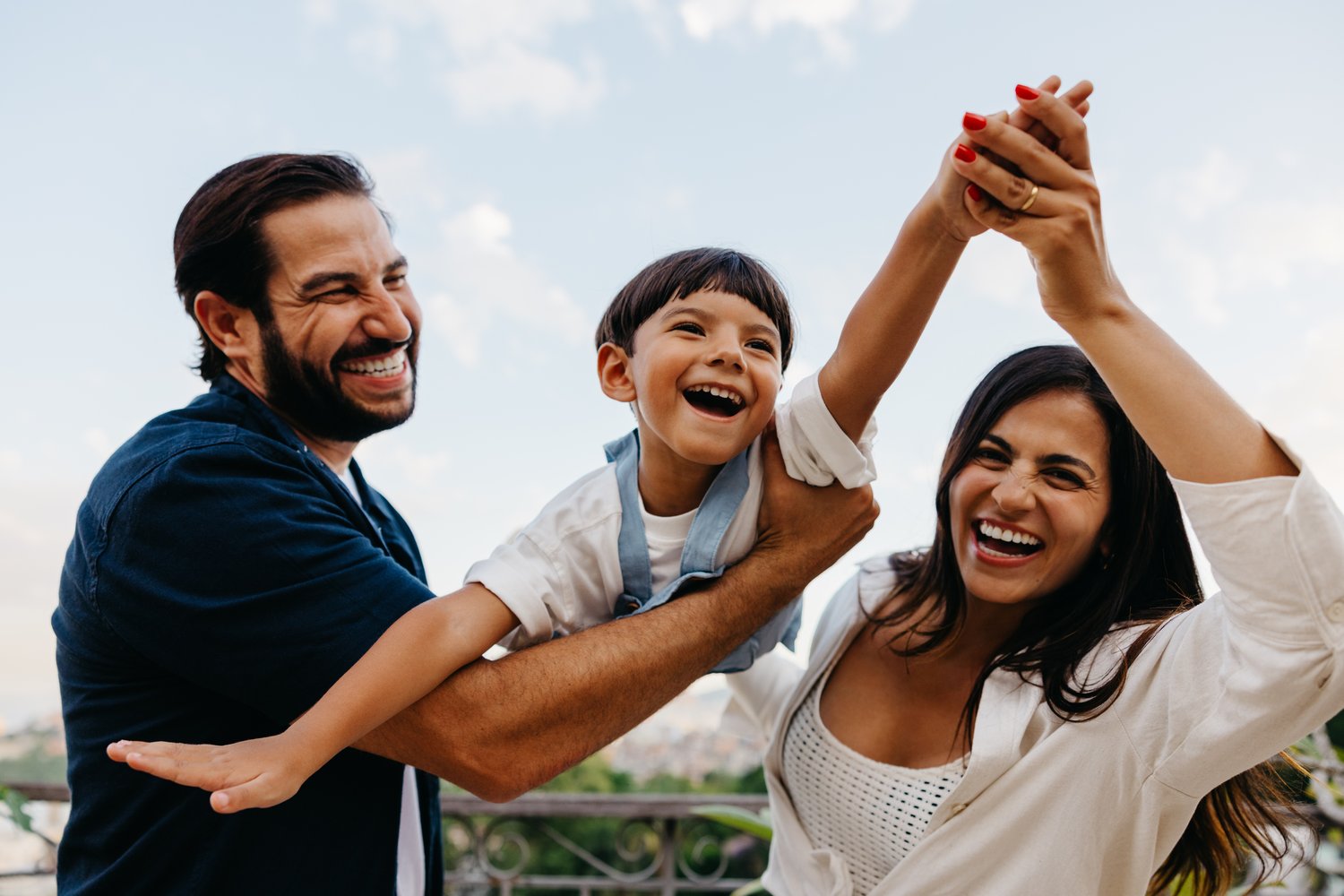 Familia riendo mientras los padres levantan a su hijo