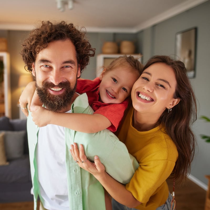 Padre, madre e hija abrazados y sonriendo en casa